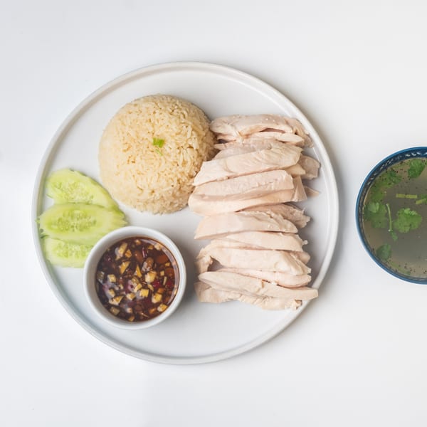 KorKai Thai Restaurant's Khao Man Gai with sliced chicken, rice, cucumbers, dipping sauce, and soup.