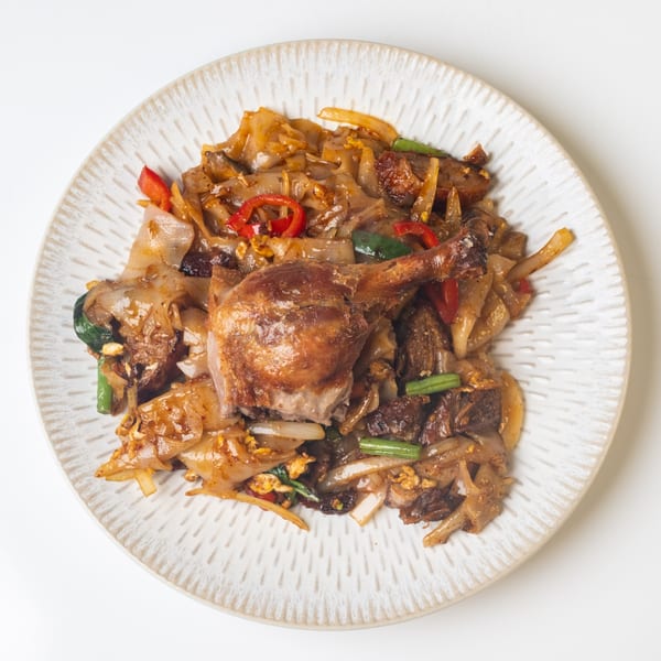 KorKai Thai Restaurant's duck pad see ew, featuring crispy duck leg, wide noodles, and vegetables.